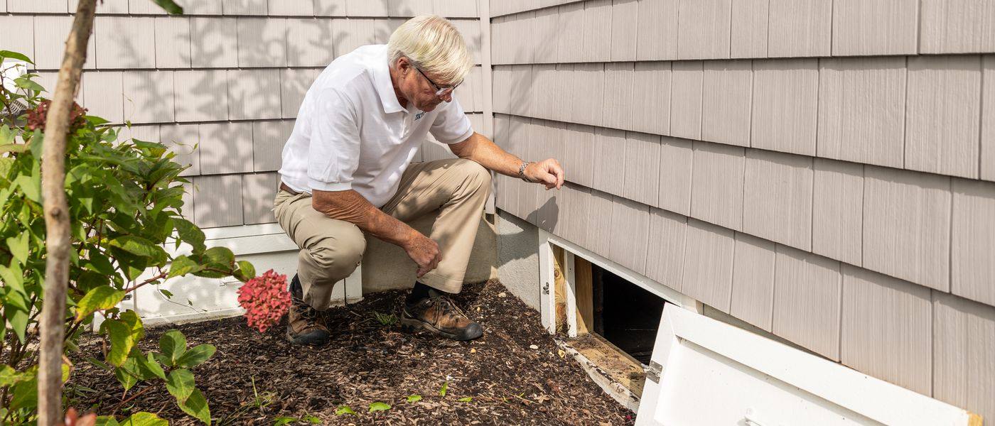 Radon specialist inspecting a crawl-space opening for mitigation planning in Lexington